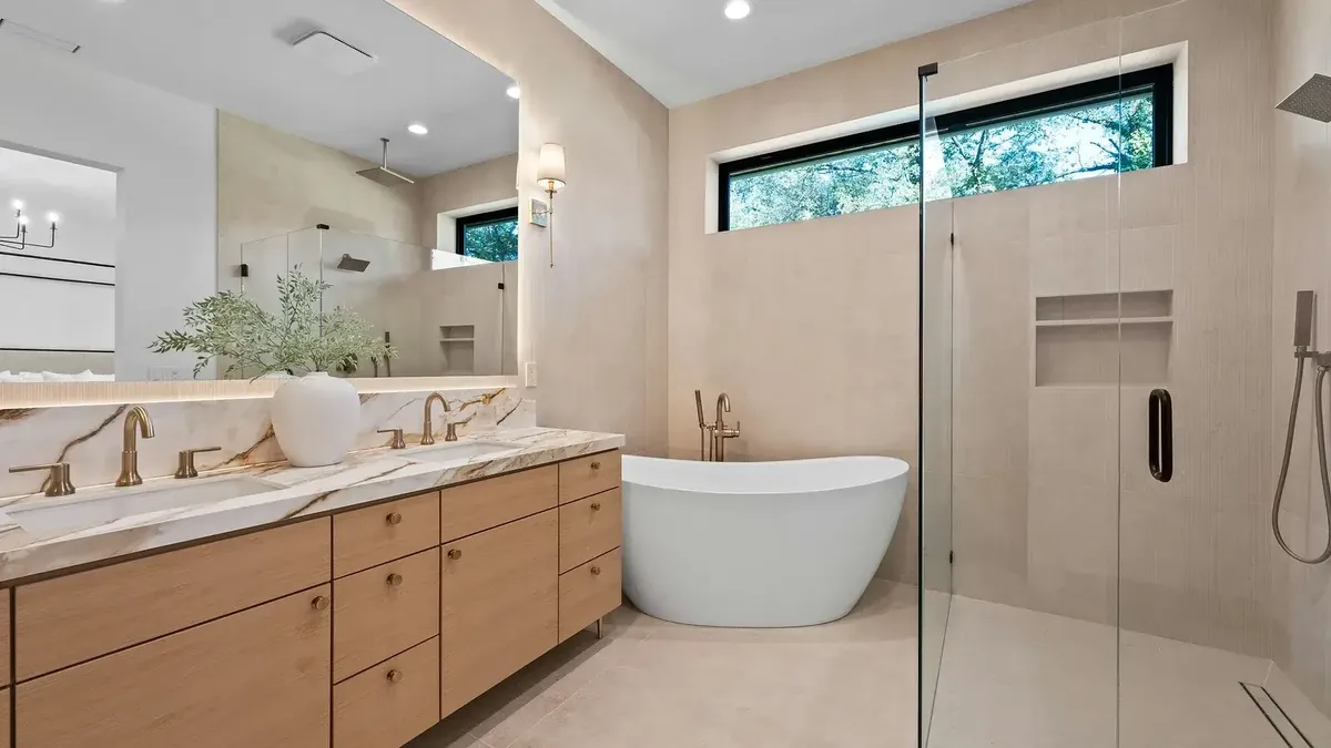 Temsilî görsel (Unsplash, GoodLifeConstruction): ahşap çift lavabo dolabı, serbest duran küvet ve cam duşakabin